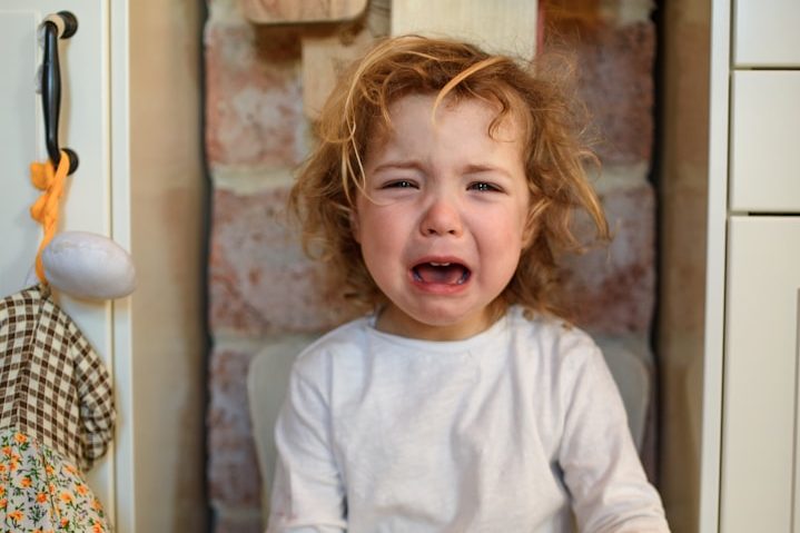 Kleine Herzen, große Gefühle - emotionale Entwicklung begleiten Kleines Kind mit lockigen Haaren, weint vor einer Steinwand.