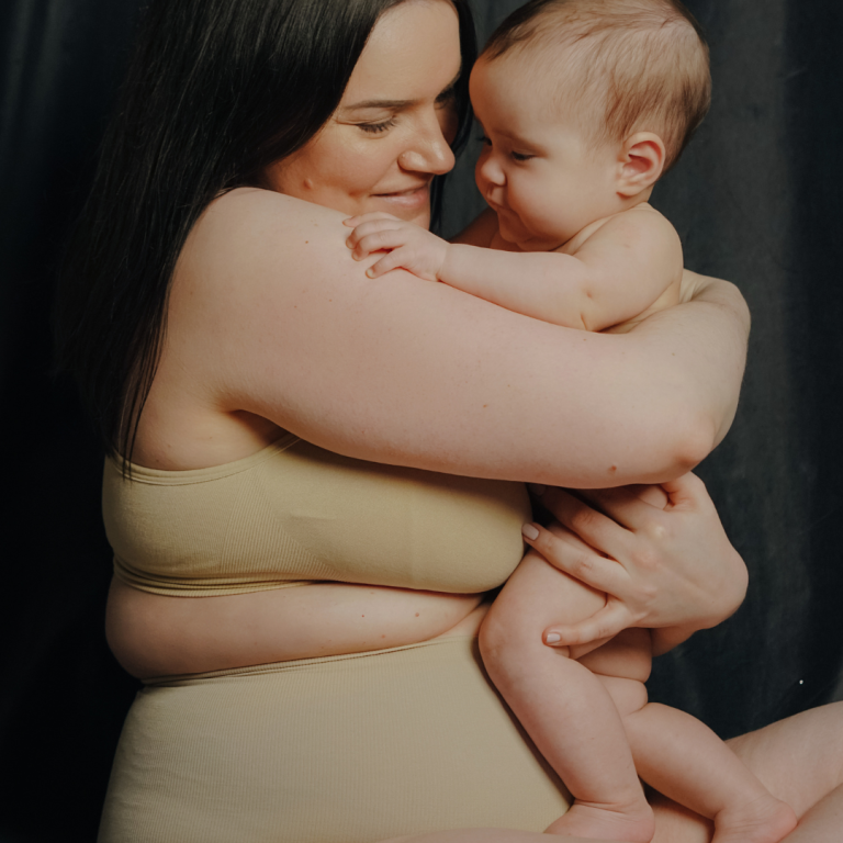 Schwangere Person formt mit Händen ein Herz auf ihrem Bauch.