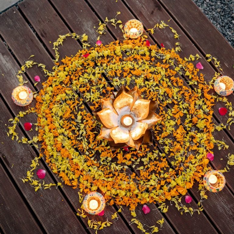 Blumenmandala aus bunten Blüten und Kerzen.