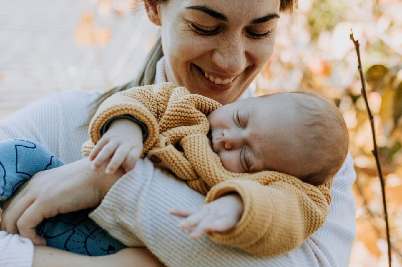 Neue Rolle, neues Glück - Ankommen in der neuen Lebensrealität Lächelnde Frau hält schlafendes Baby in einer warmen Umgebung.