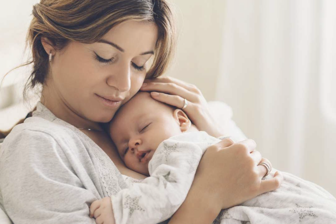 Eine Frau hält ein schlafendes Baby in liebevoller Umarmung.