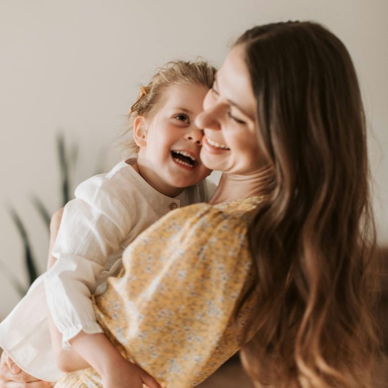 Frau tränenverschmierter Schminke hält ein Blatt mit einem lächelnden Gesicht vor sich.