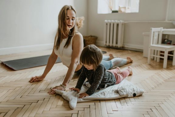 Mutter und Kind machen spielerisch und entspannt zusammen Mama-Kind Yoga.