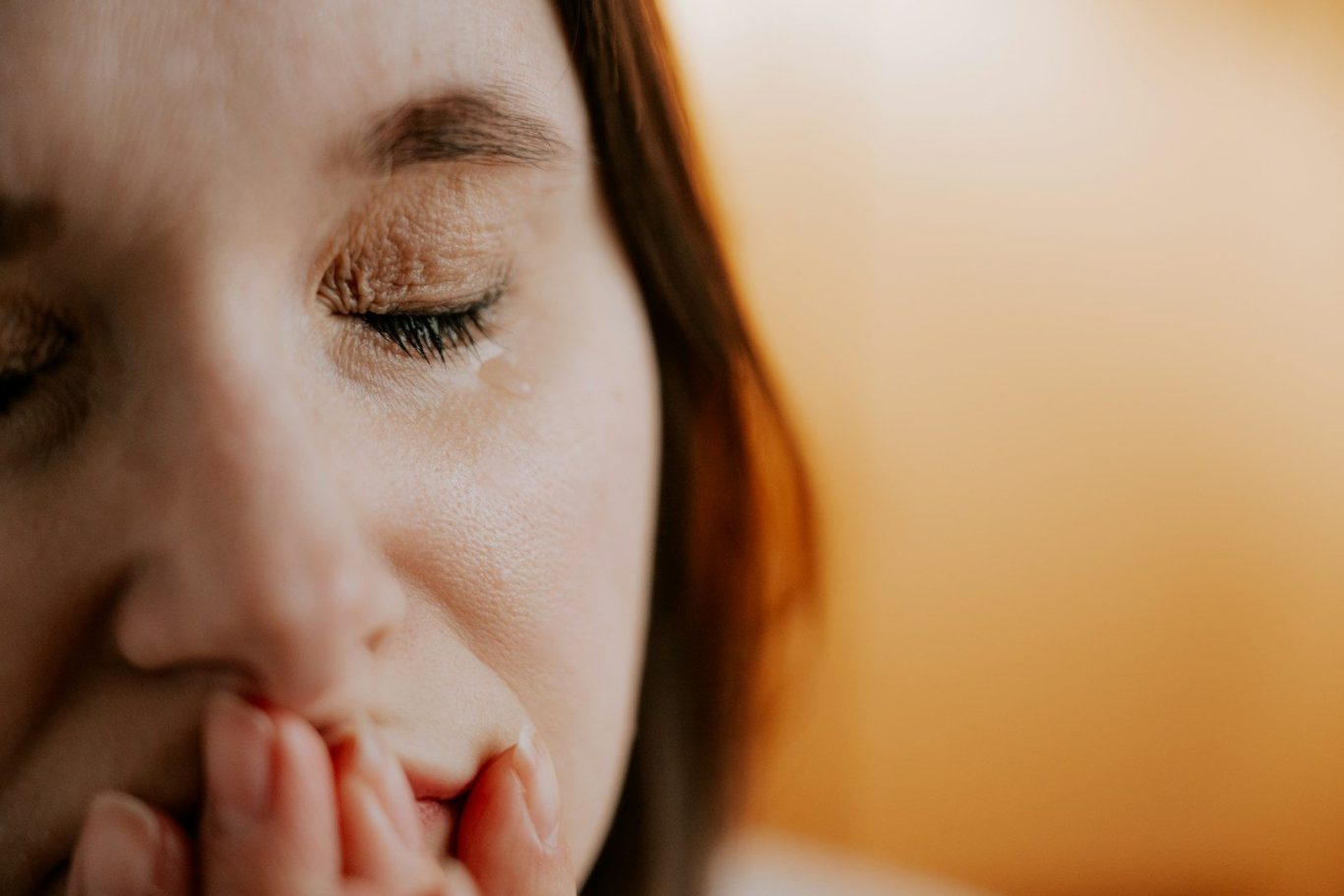 Balance im Hormonchaos - Emotionen in der Schwangerschaft Frau mit besorgtem Gesichtsausdruck hält ihre Hände vor dem Mund.