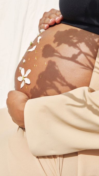 Bauch einer schwangeren Frau, liebevoll mit Blüten verziert